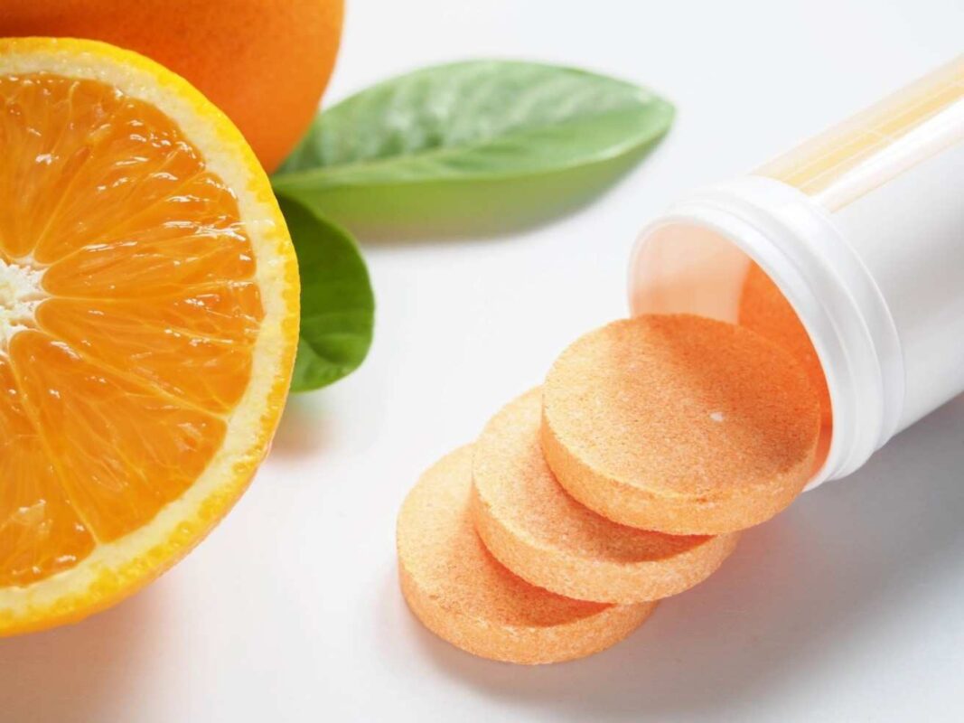 Vitamin C Tablets for Immunity with fresh oranges and juice promoting natural health and strong immune system.