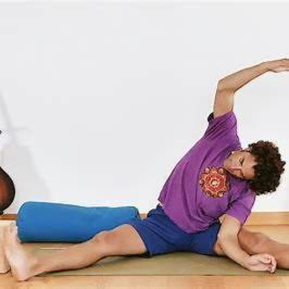A person practices a seated side stretch on a yoga mat at home, demonstrating how gentle movements and mindful stretching can be easily integrated into a daily recovery routine.