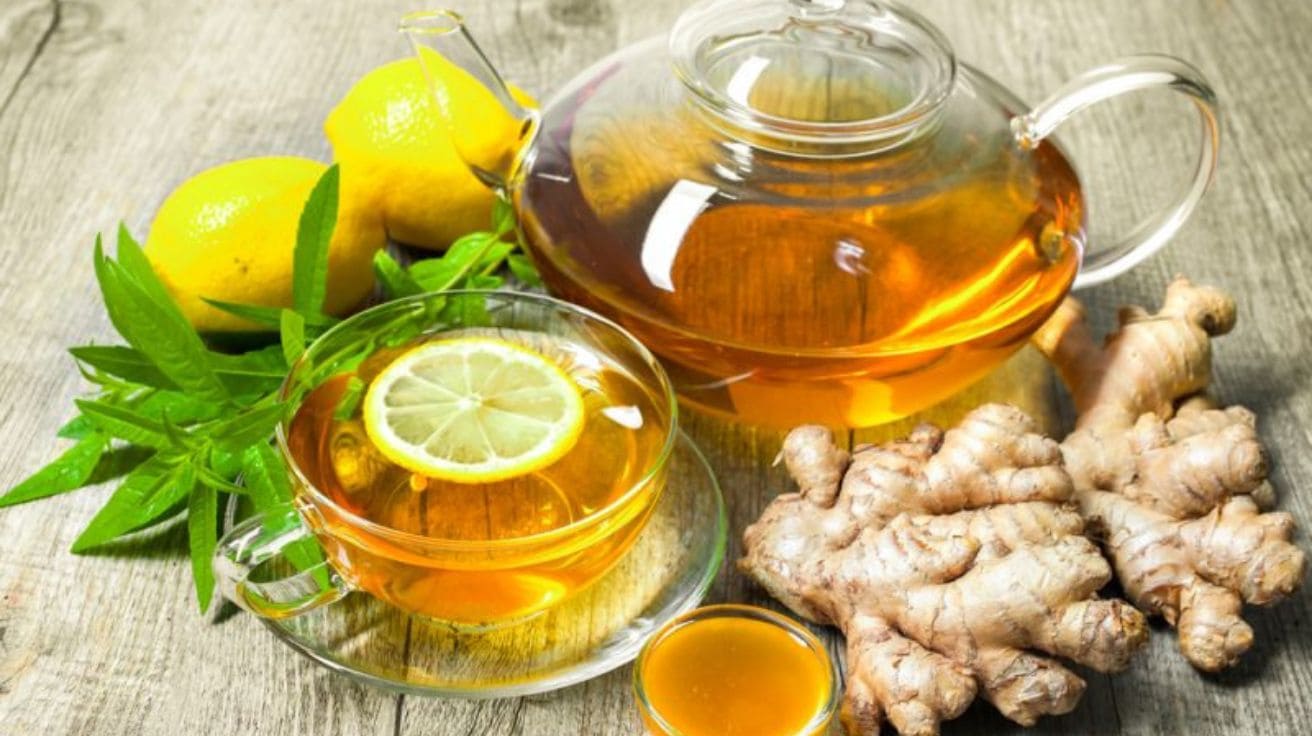 A steaming cup of ginger tea with fresh ginger slices on a rustic wooden surface, representing natural stomach pain relief.